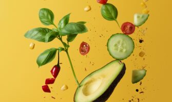 Un aguacate sobre un fondo amarillo y algunos vegetales