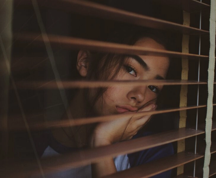 chica triste mirando por la ventana