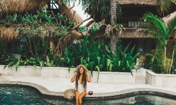 Young happy woman relaxing on poolside. Travel and vacations in Asia. Straw hat and white swimsuit. bronceado