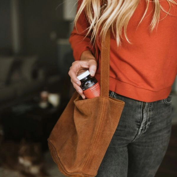 Una mujer saca del bolso un bote de suplementos naturales