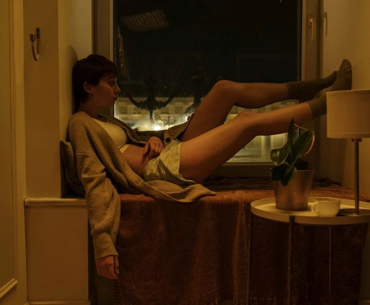 pexels-cottonbro-6951882 Persona sentada en el alféizar de una ventana, de noche, con gesto de insomnio y desesperación tras levantarse por dar vueltas en la cama