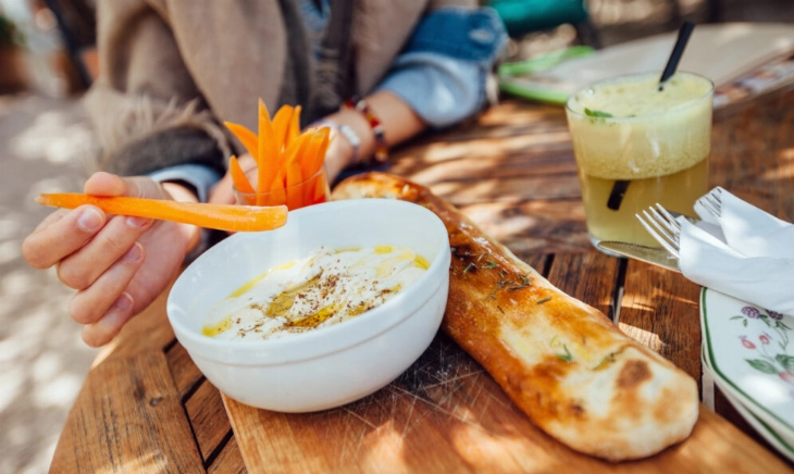 Mujer comiendo hummus, que, gracias a los garbanzos, es rico en fitoestrógenos.