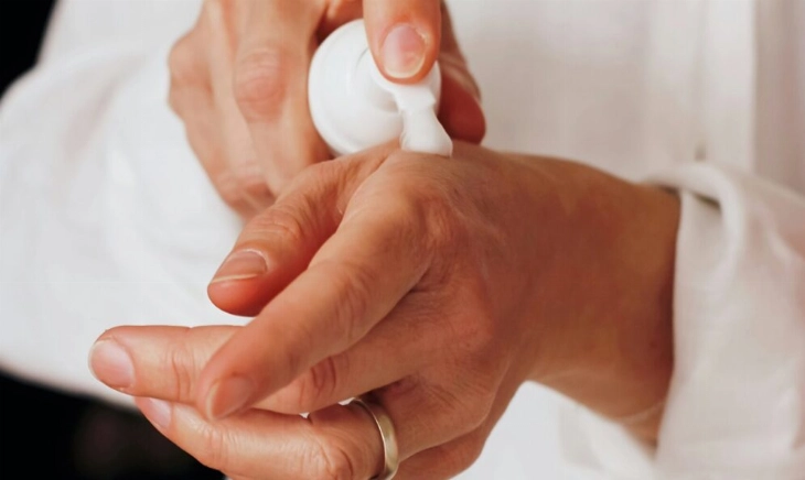 Una mujer aplicándose crema hidratante en las manos