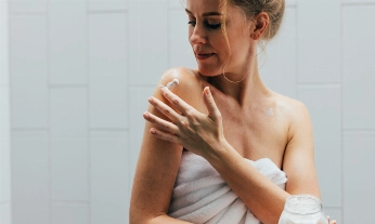 Una mujer aplicándose crema de cuerpo