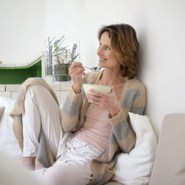 Mujer comiendo un yogur, un probiótico clave en la dieta antiinflamatoria