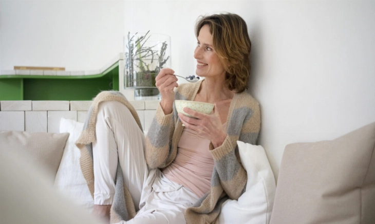 Mujer comiendo un yogur, un probiótico clave en la dieta antiinflamatoria