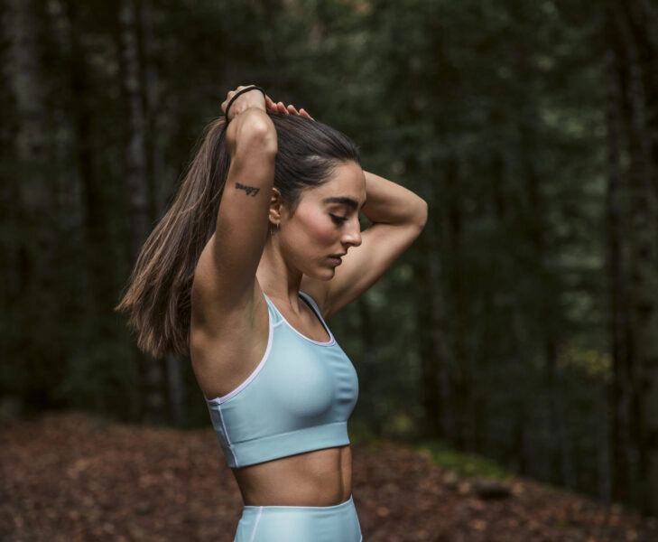 Woman making ponytail while standing in forest