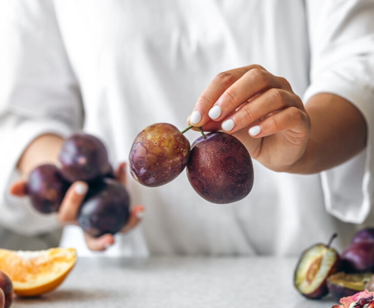 Plums in the hands of a woman in the kitchen.