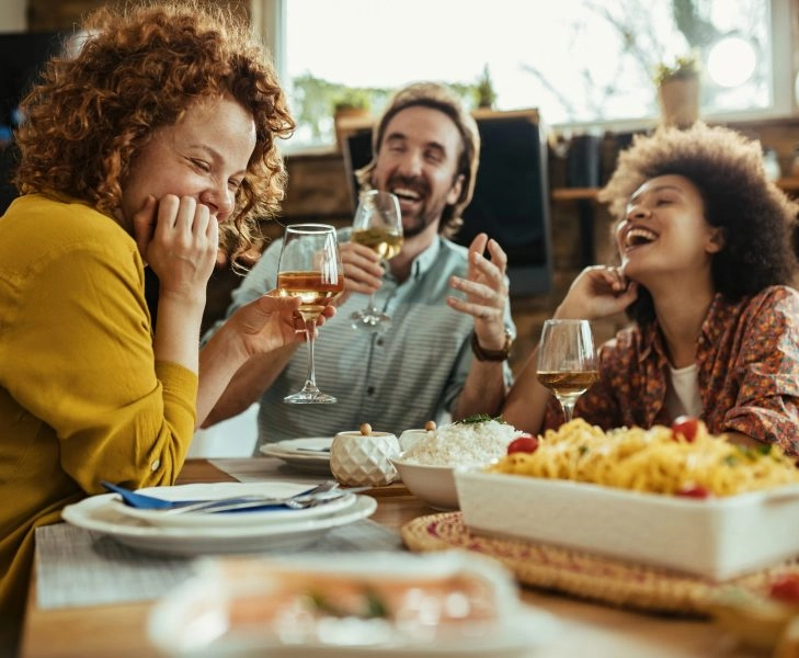 Cheerful woman having fun with her friends at dining table.
