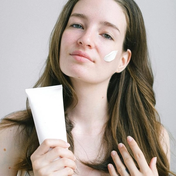 Una chica joven usando crema y tal vez sobretratando su piel