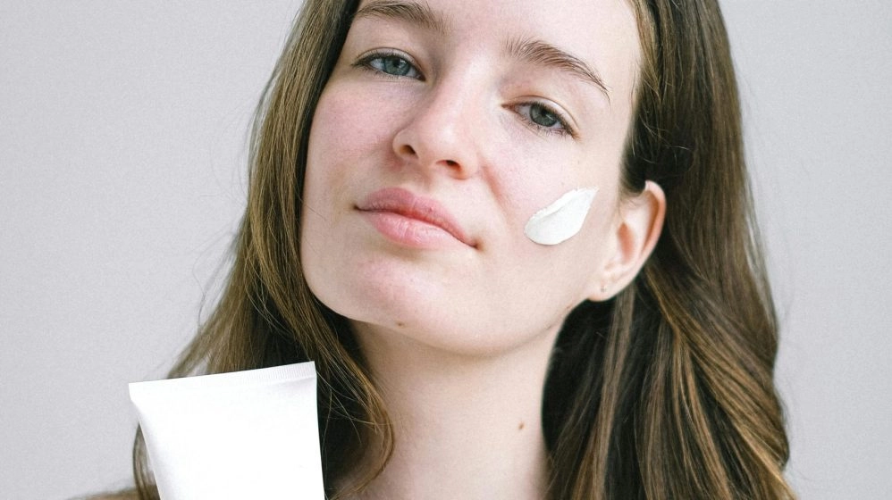 Una chica joven usando crema y tal vez sobretratando su piel