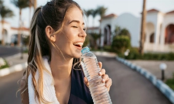 Closeup portrait excited happy young woman smiling with closed eyes to sun with bottle of water. Attractive sportswoman, enjoying summer, training, outwork, happiness.