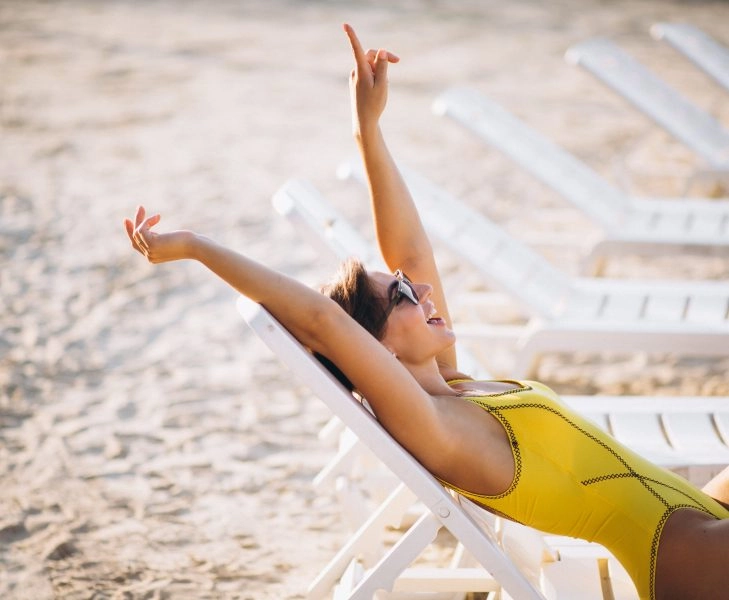 Woman lying on pool bed by the sea