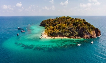Aerial shot of a small green island in the middle of the ocean