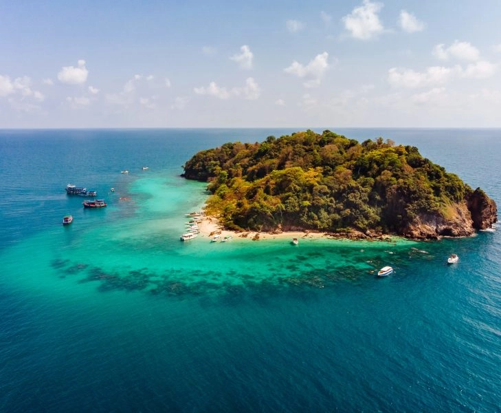 Aerial shot of a small green island in the middle of the ocean