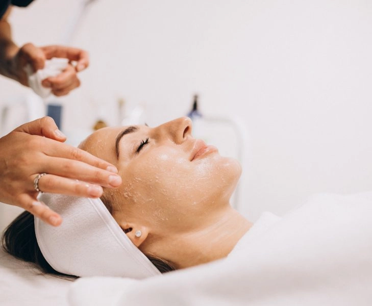 Cosmetologist cleaning face of a woman in a beauty salon