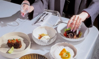 Platos de alta gastronomía saludable en mesa de restaurante, con copa de cristal vacía como maridaje sin alcohol.