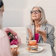 Mujer mayor con canas tomando algo en una cafetería, reflejo del envejecimiento natural y de cómo los hábitos cotidianos influyen en la edad de tu intestino
