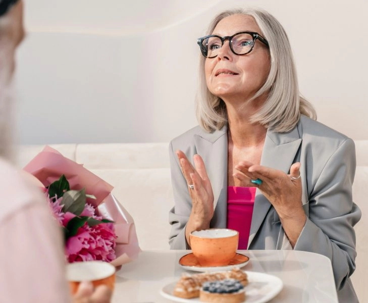 Mujer mayor con canas tomando algo en una cafetería, reflejo del envejecimiento natural y de cómo los hábitos cotidianos influyen en la edad de tu intestino