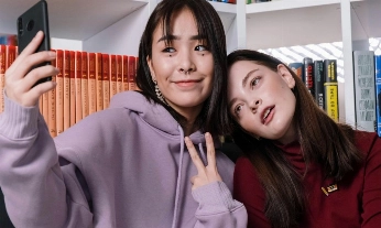 Dos chicas haciéndose un selfie; una sonríe y la otra pensando no me reconozco en las fotos, sorprendida al verse distinta