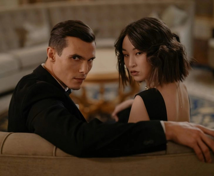 pareja elegante sentada en un sofá mirándose con desconfianza, mentiras en pareja