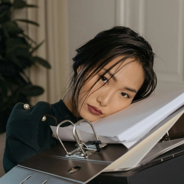 “por qué odio los lunes”: mujer recostada sobre archivadores en la oficina, expresión de agotamiento