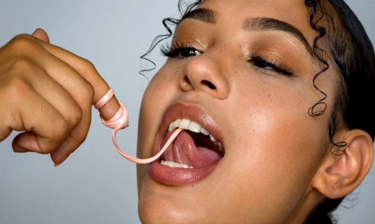 mujer estirando un chicle con la boca, símbolo de un remedio rápido para el mal aliento