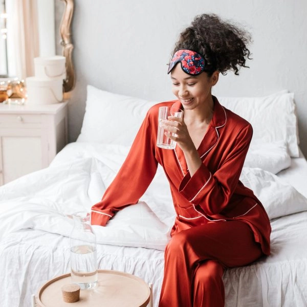 Mujer recién despierta bebiendo agua para aliviar la boca seca por la noche