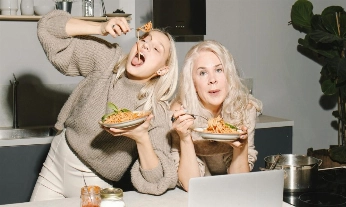 Madre e hija comiendo un plato de espaguetis, ejemplo de comida cotidiana donde la calidad de las calorías marca la diferencia