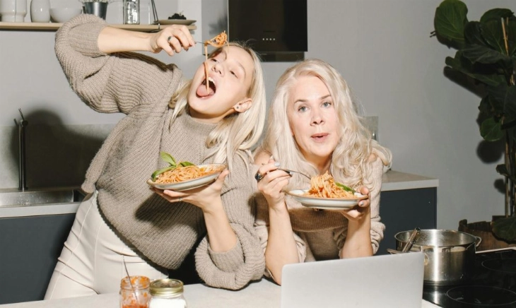 Madre e hija comiendo un plato de espaguetis, ejemplo de comida cotidiana donde la calidad de las calorías marca la diferencia
