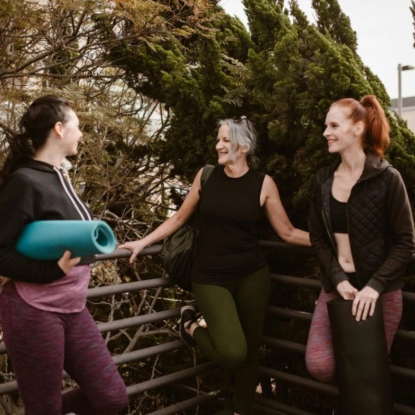 Tres mujeres de mediana edad en mallas de yoga conversan relajadas antes de las charlas de ASISA WeLife Menopausia