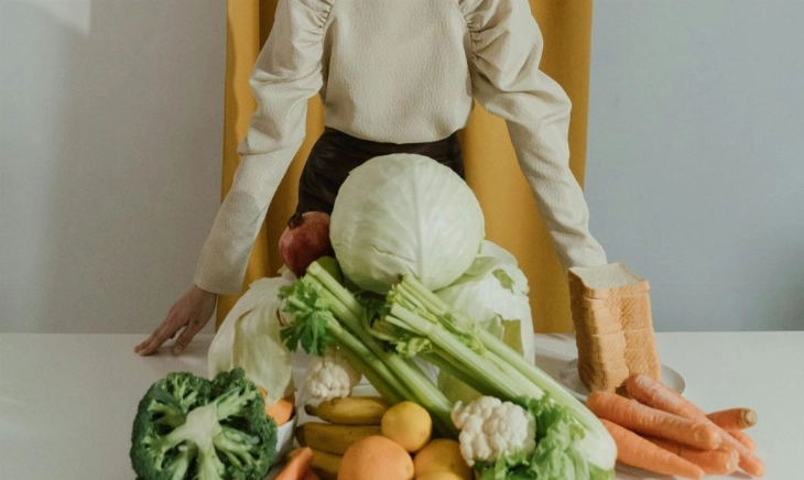 Mujer con alimentos saludables y mala cara por no comer sano