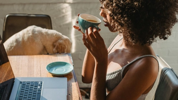 Mujer trabajando con portátil con una taza de café, ideal para ilustrar artículo sobre café y sueño