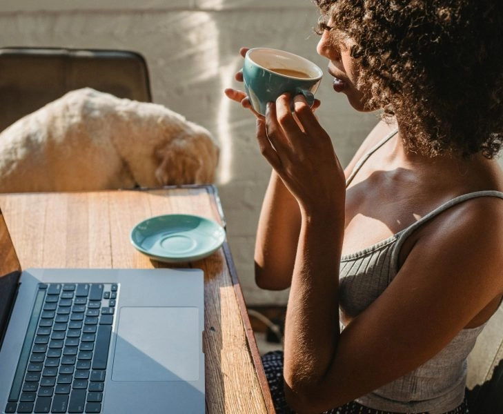 Mujer trabajando con portátil con una taza de café, ideal para ilustrar artículo sobre café y sueño