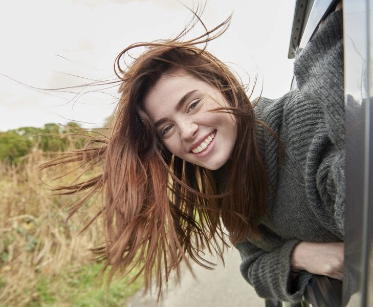 Young woman with head out of car window Mujer sin filtros de belleza que arruinan la autioestima