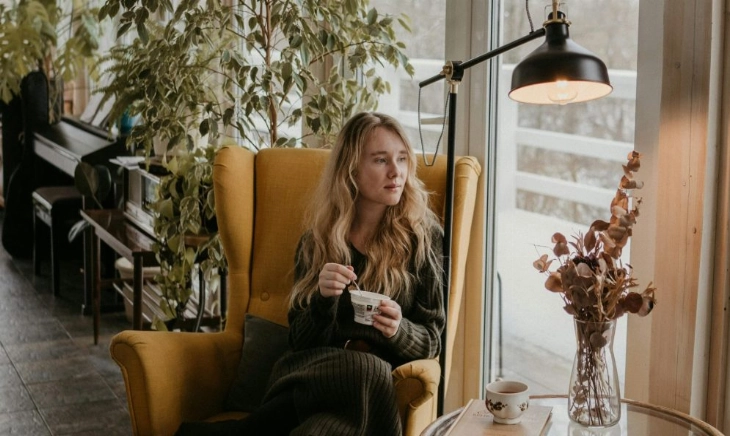 Mujer desayunando yogur junto a la ventana, el mejor momento para tomar yogur según los expertos