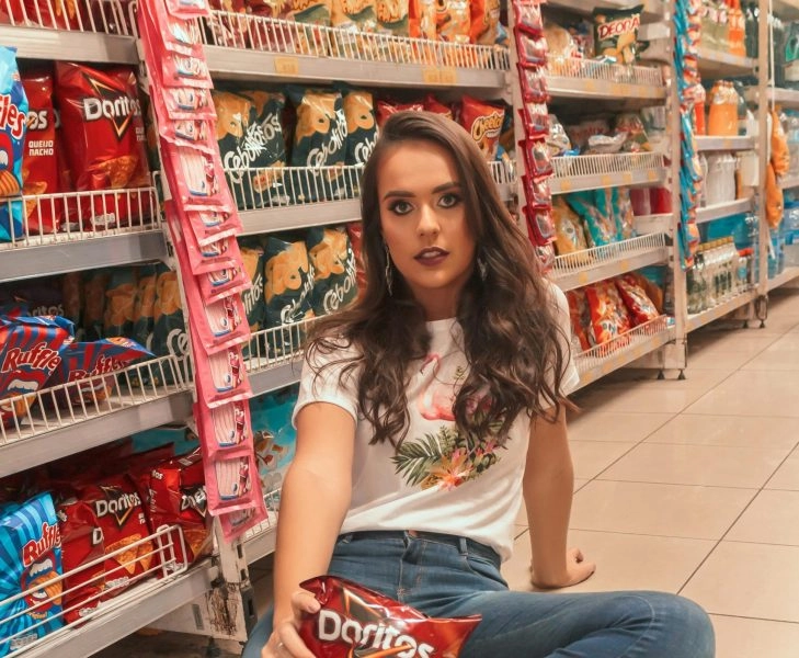 Mujer en un supermercado con aperitivos que ilustran la contradicción de los productos light que engordan y el placer de comer.