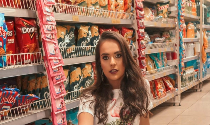 Mujer en un supermercado con aperitivos que ilustran la contradicción de los productos light que engordan y el placer de comer.