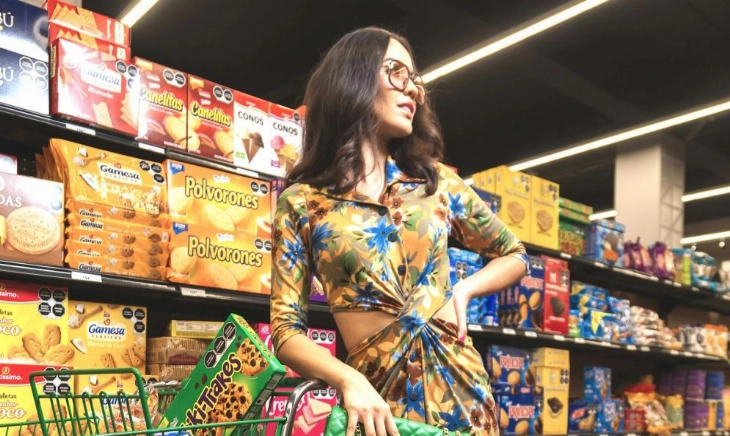 Mujer en el supermercado leyendo etiquetas de los alimentos entre productos ultraprocesados