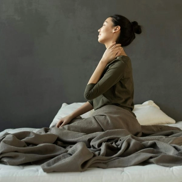 Mujer despierta con cansancio en la cama, reflejando cómo dormir poco aumenta el riesgo cardiovascular y acelera el envejecimiento del cuerpo