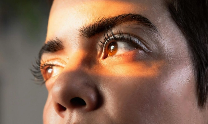 Primer plano de una mujer con luz natural sobre el rostro, símbolo de la caída de cejas y pestañas durante el otoño