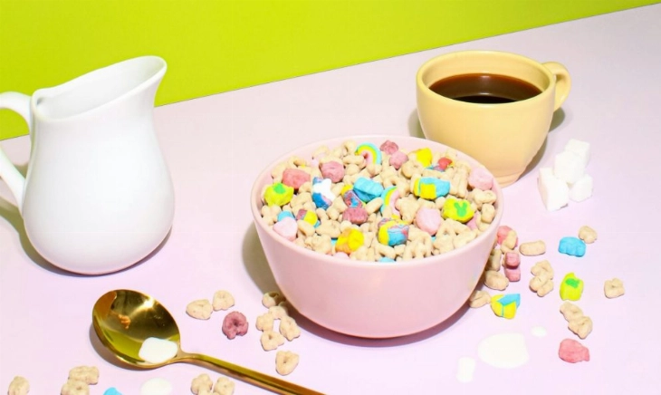 Bol de cereales de colores junto a una taza de café y una jarra de leche, imagen alusiva a la tendencia de cenar cereales