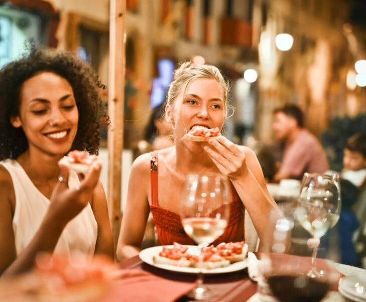 Dos mujeres cenan al aire libre entre risas, un ejemplo involuntario de hara hachi bu antes de que se pusiera de moda