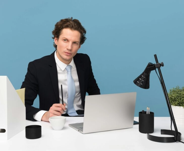 perfeccionismo relativo hombre joven con traje trabajando frente a un ordenador portátil, gesto concentrado, concepto de perfeccionismo relativo