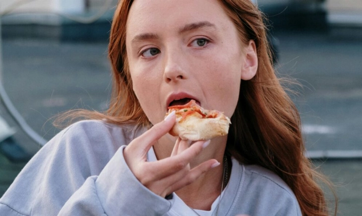 Persona comiendo al aire libre en una ciudad; la escena ilustra cómo el entorno urbano —poco verde, ruido y dependencia del coche— condiciona hábitos y puede favorecer el aumento de peso