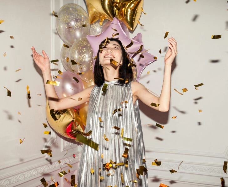 Mujer celebrando entre confeti y globos en una fiesta navideña, símbolo de cómo no hincharte en Navidad disfrutando sin excesos
