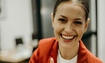 Mujer joven sonriendo y haciendo un gesto de aprobación con el pulgar, imagen que refleja el espíritu del playfulness y el bienestar ligero