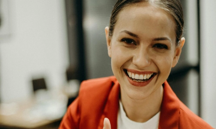 Mujer joven sonriendo y haciendo un gesto de aprobación con el pulgar, imagen que refleja el espíritu del playfulness y el bienestar ligero