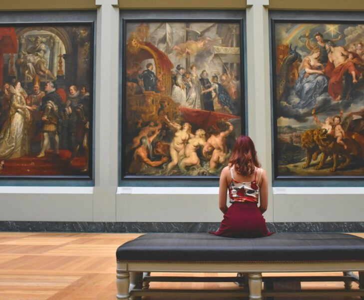 museo beneficios mente meditacion Mujer sentada frente a grandes pinturas en un museo, imagen que refleja los beneficios del museo para la mente y la meditación