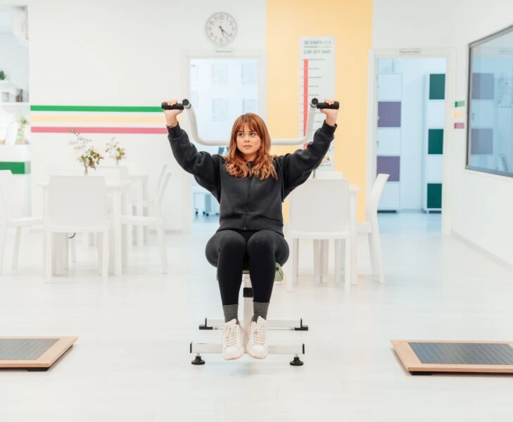 postura-corporal-entrenar Mujer entrenando en un gimnasio, concentrada en mantener una postura correcta mientras realiza un ejercicio de fuerza